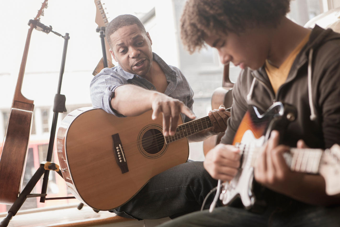 Guitar coach helping his student learn to play the guitar.
